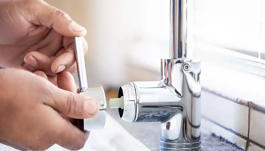 Plumber installing a kitchen sink faucet in a residential home