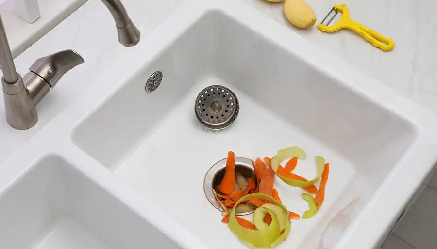Technician repairing a kitchen garbage disposal under the sink
