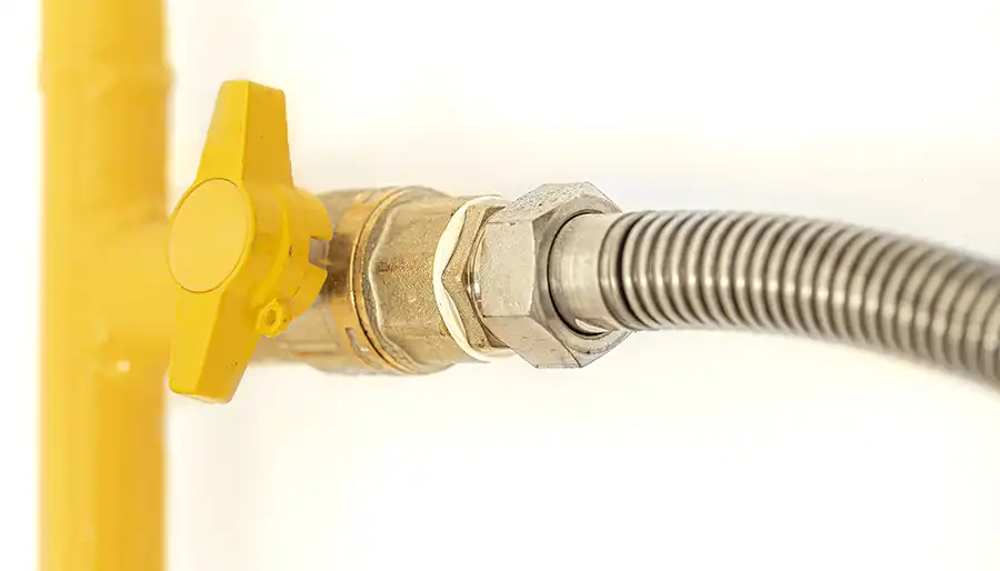 Technician installing a residential gas line connection for an appliance