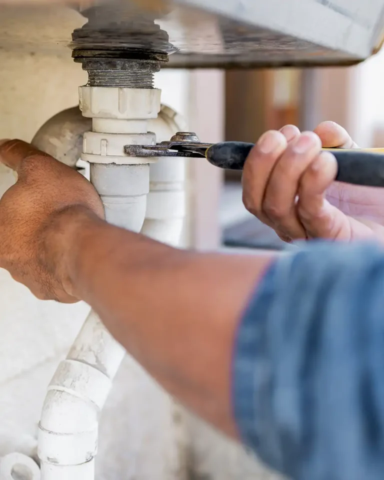 Plumber Englewood working on PVC pipes under a residential sink